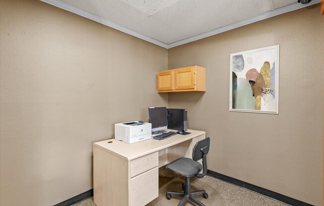 a desk with a computer and a printer in a room