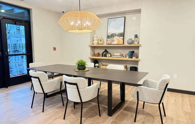 a dining space with a table and chairs and inset shelves with decor along back wall