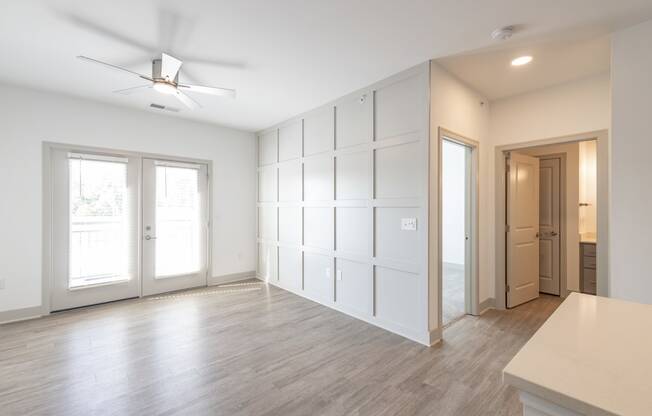 an empty living room with white walls and a ceiling fan