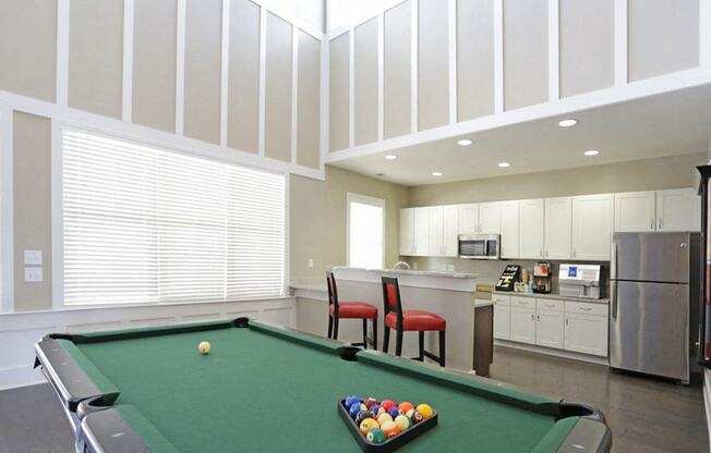 a game room with a pool table and a kitchen