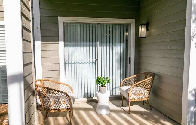 a porch with two rattan chairs and a vase with a plant at Briarcliff Apartments, Atlanta