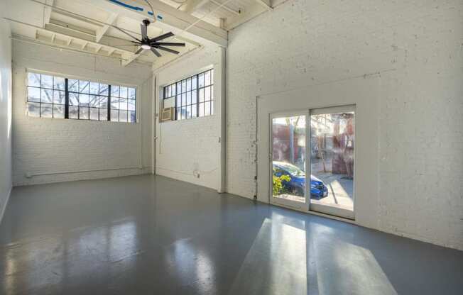 a large empty room with windows and a ceiling fan