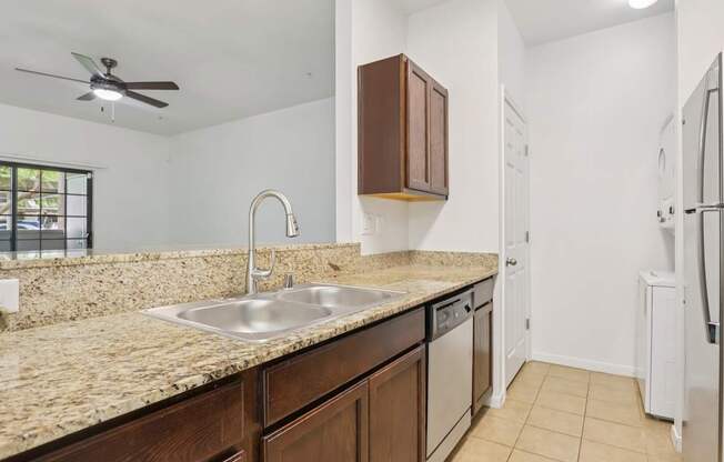 A kitchen with a sink, refrigerator, and cabinets.