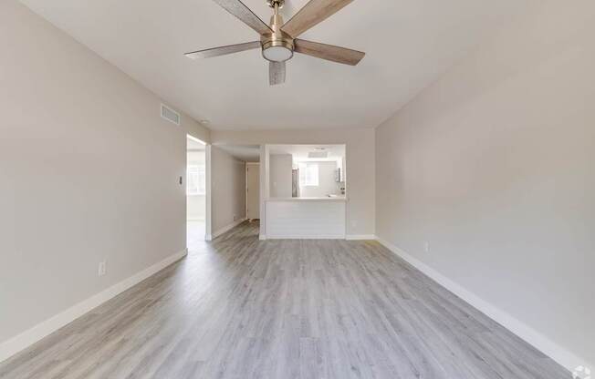 an empty living room with a ceiling fan