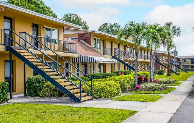 a row of yellow houses with stairs and palm trees