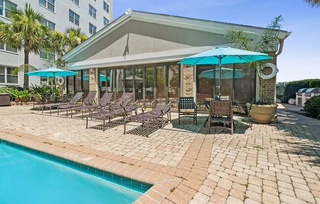 A poolside area with a blue umbrella and chairs.
