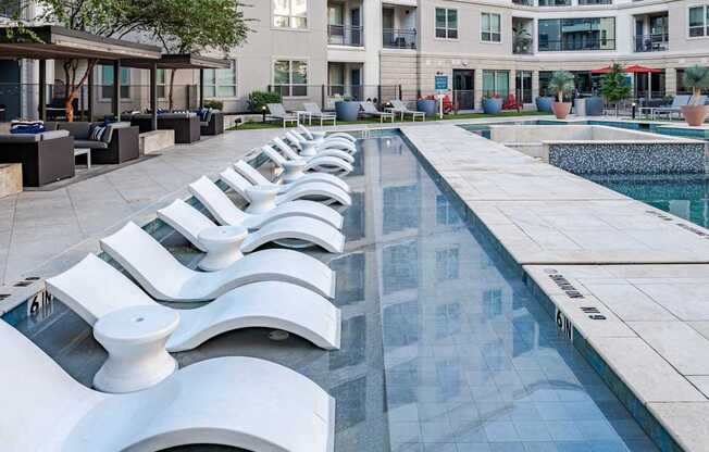 A pool with white chairs around it.