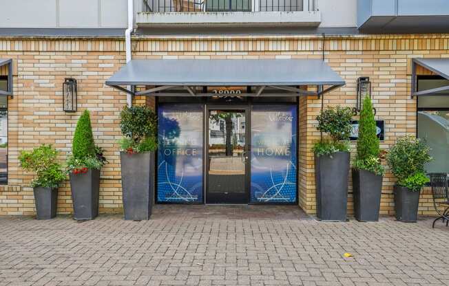 the front of a brick building with doors and potted plants