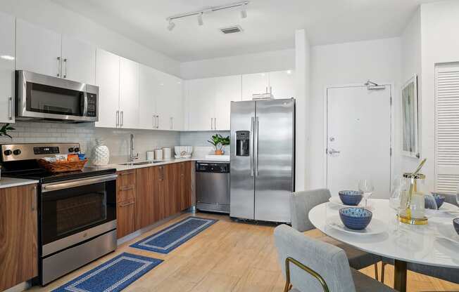 a kitchen with white cabinets and stainless steel appliances and a white table and chairs