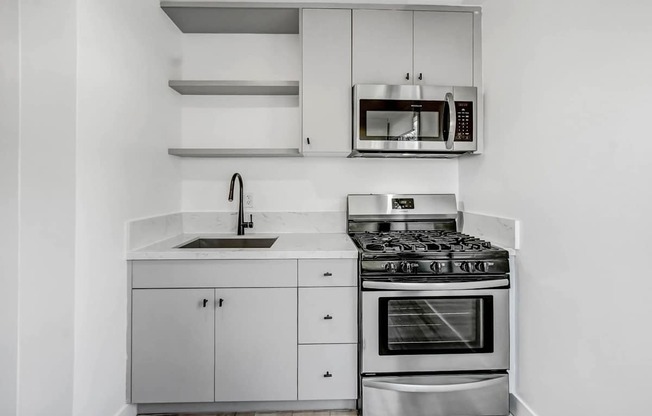 A modern kitchen with a stove, sink, and cabinets.