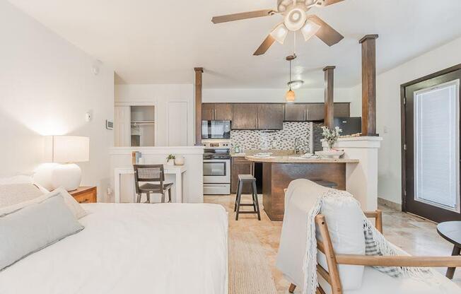 a living room and kitchen with a bed and a ceiling fan