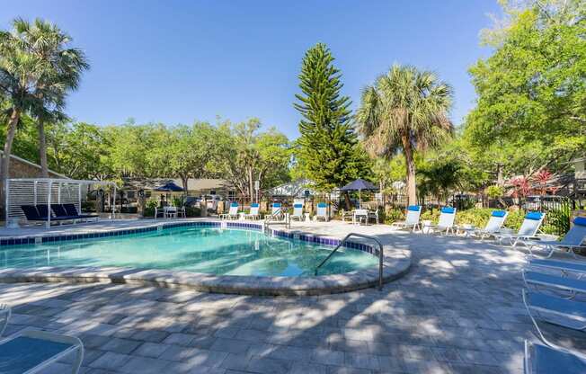 a pool with lounge chairs and trees in the background