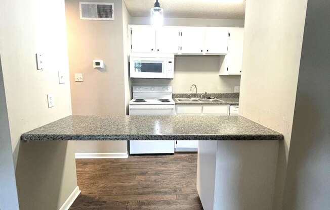 A kitchen with a granite countertop and white cabinets.