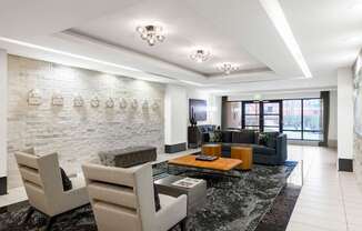 Two chairs and a table are in a room with a white brick wall.