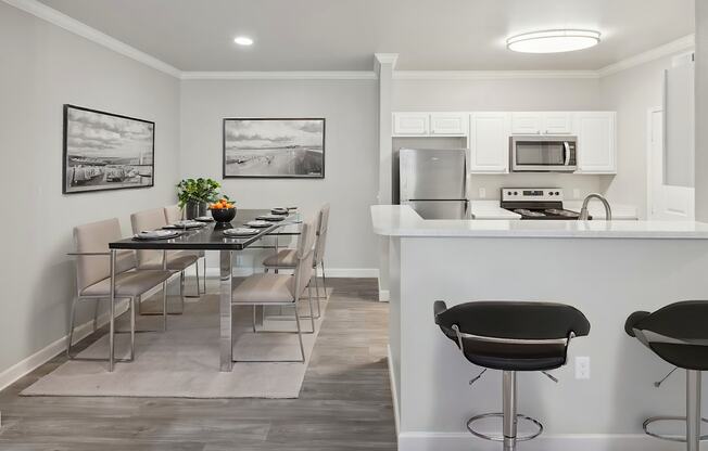 A kitchen with a bar stool and a dining table.