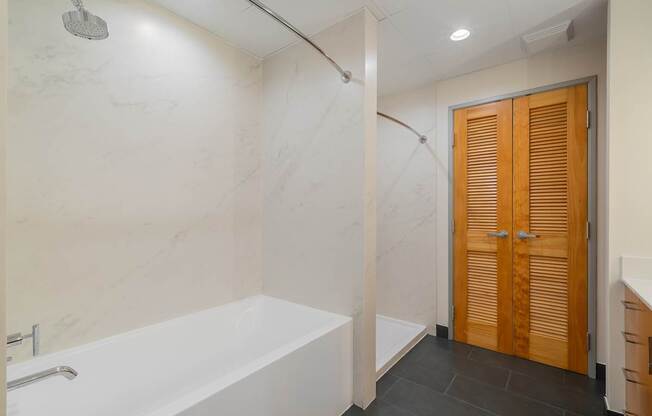 A white bathtub in a bathroom with a wooden door.