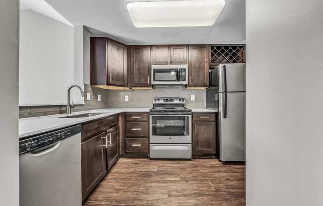 an empty kitchen with stainless steel appliances and wooden cabinets