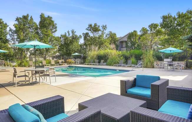 a swimming pool with patio furniture and umbrellas