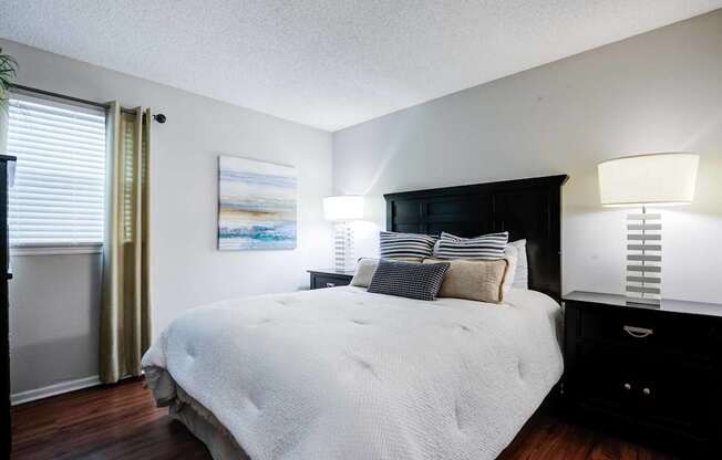 A bedroom with a large bed and a painting on the wall.