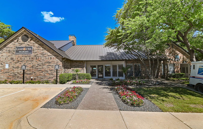 a view of the front of the building with a tree and flowers in front of it
