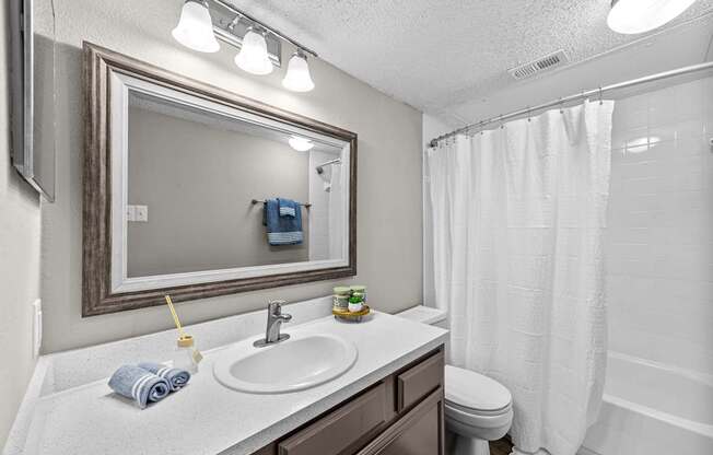 A bathroom with a white sink, toilet, and shower curtain.