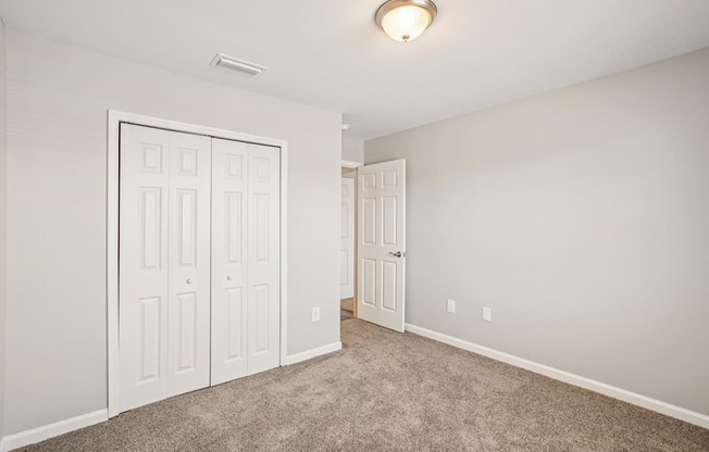 A room with a carpeted floor and two white doors.