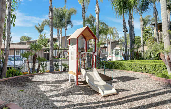 A playground with a red and white structure and a slide.