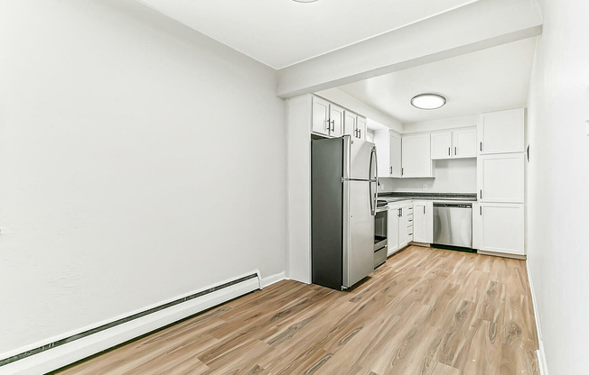 Bright, contemporary kitchen with sleek stainless steel appliances, modern white cabinetry, and elegant wood flooring, offering a perfect blend of style and functionality.