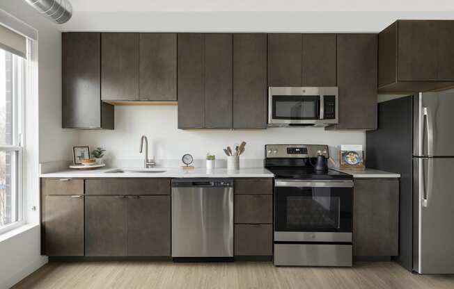 a kitchen with dark cabinets and stainless steel appliances