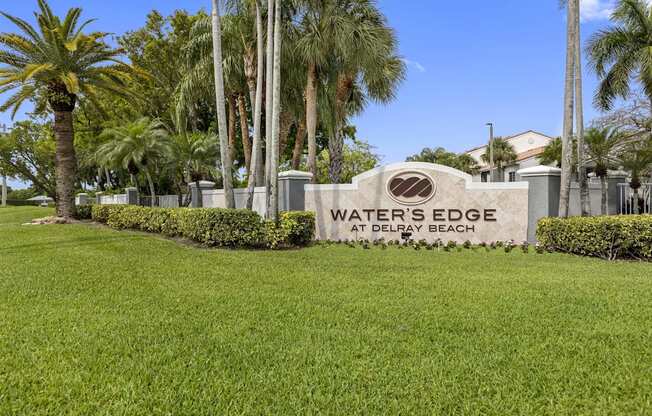 the waters edge at drew beach sign in front of palm trees