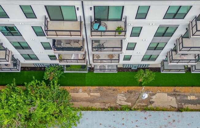 an aerial view of an apartment building with green grass and trees in front of it