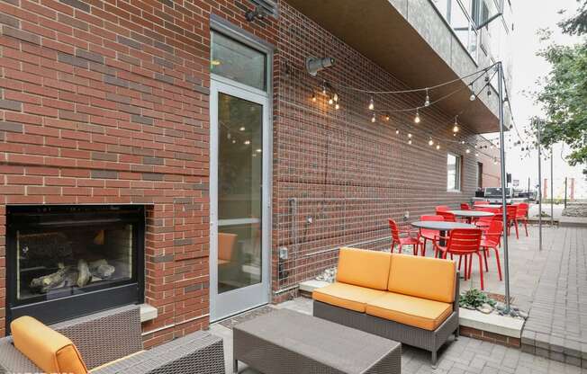 a patio with couches and chairs and a fire place on the side of a building