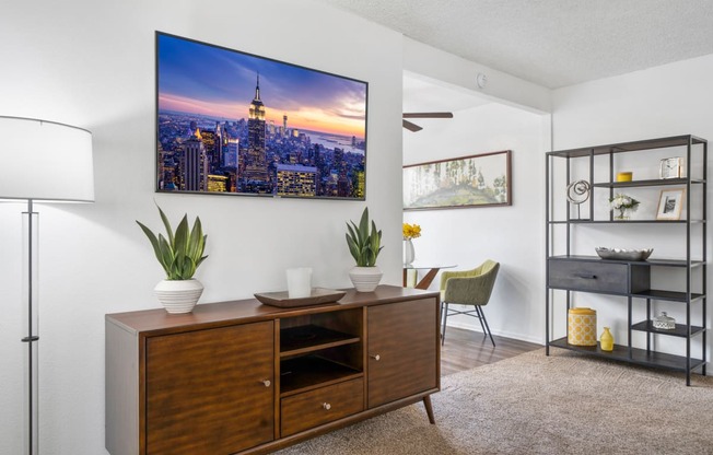 a living room with a desk and a wall mounted picture of a city skyline