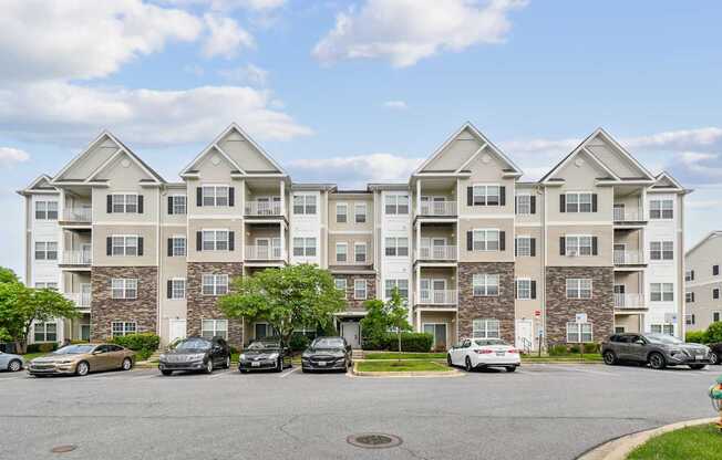 A large apartment building with cars parked in front.