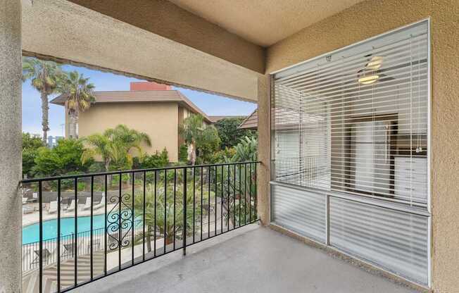 A balcony with a pool and palm trees in the background.