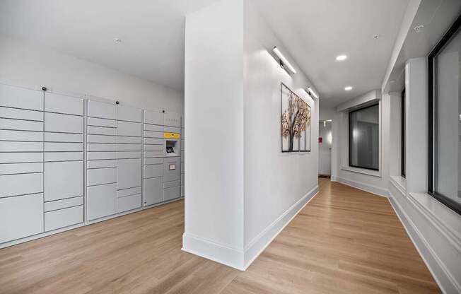 A long hallway with a white wall and a brown floor.