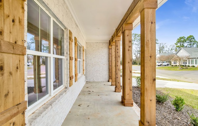 the front porch of a building with wood posts and windows