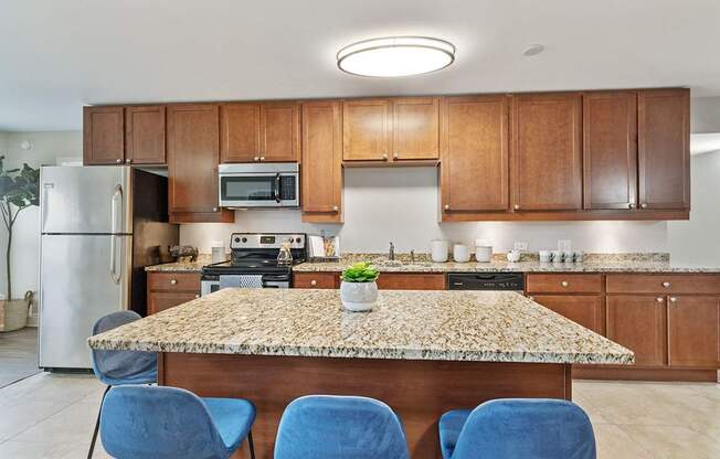 A kitchen with a granite countertop and blue chairs.