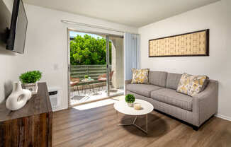 A living room with a grey couch, a white coffee table, and a wooden cabinet.