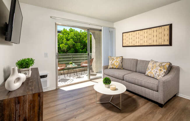A living room with a grey couch, a white coffee table, and a wooden cabinet.