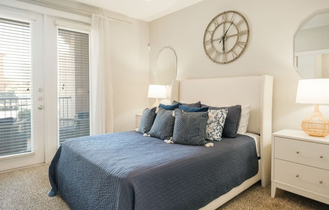 A bedroom with a bed, nightstand, and a clock on the wall.