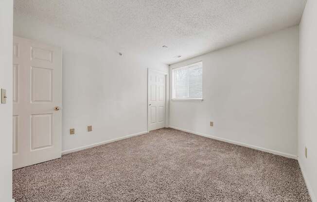 A room with a carpeted floor and a door on the left side.