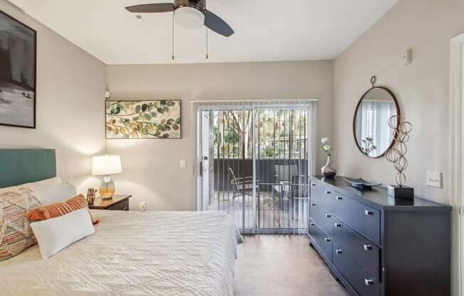 A bedroom with a bed, dresser, and a ceiling fan.