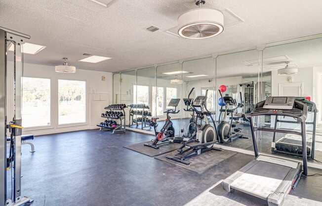 a fitness room with cardio equipment and mirrors