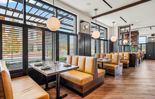 A restaurant with a long table and chairs with a view of the street outside.