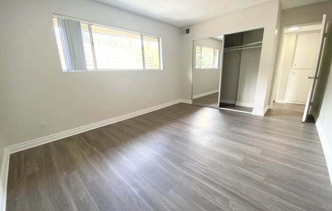 an empty living room with a wood floor and white walls