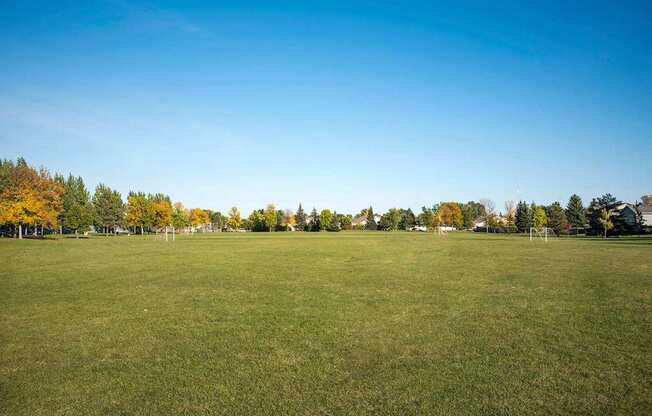 A large grassy field with trees in the background. Fargo, ND Stonebridge Apartments