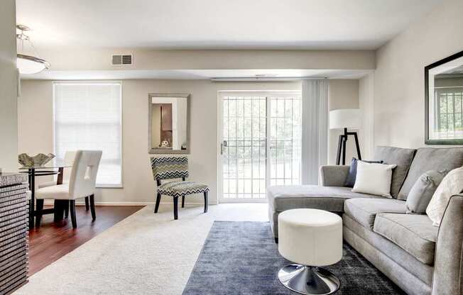 A living room with a grey couch, a white chair, and a white ottoman.