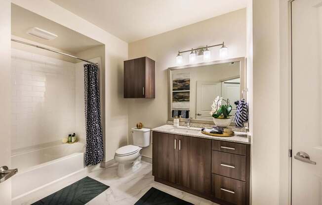 A bathroom with a white tub, a toilet, a sink, and a mirror.