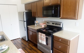 a kitchen with stainless steel appliances and brown wooden cabinets at Heritage Grove Apartments in Renton, WA